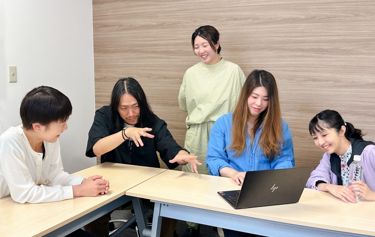 写真：パソコンを見ながら談笑する４名の女性メンバーとユニットリーダーの今村