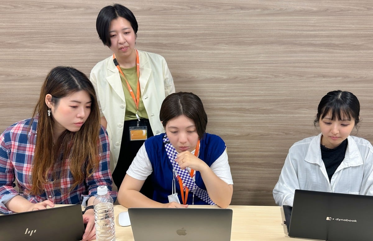 真剣な表情でパソコンを見ながら連携する４人の女性メンバー