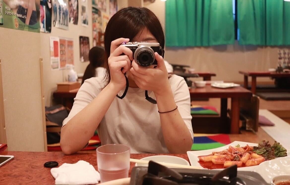 カメラを持っている田渕さん。韓国料理屋にて