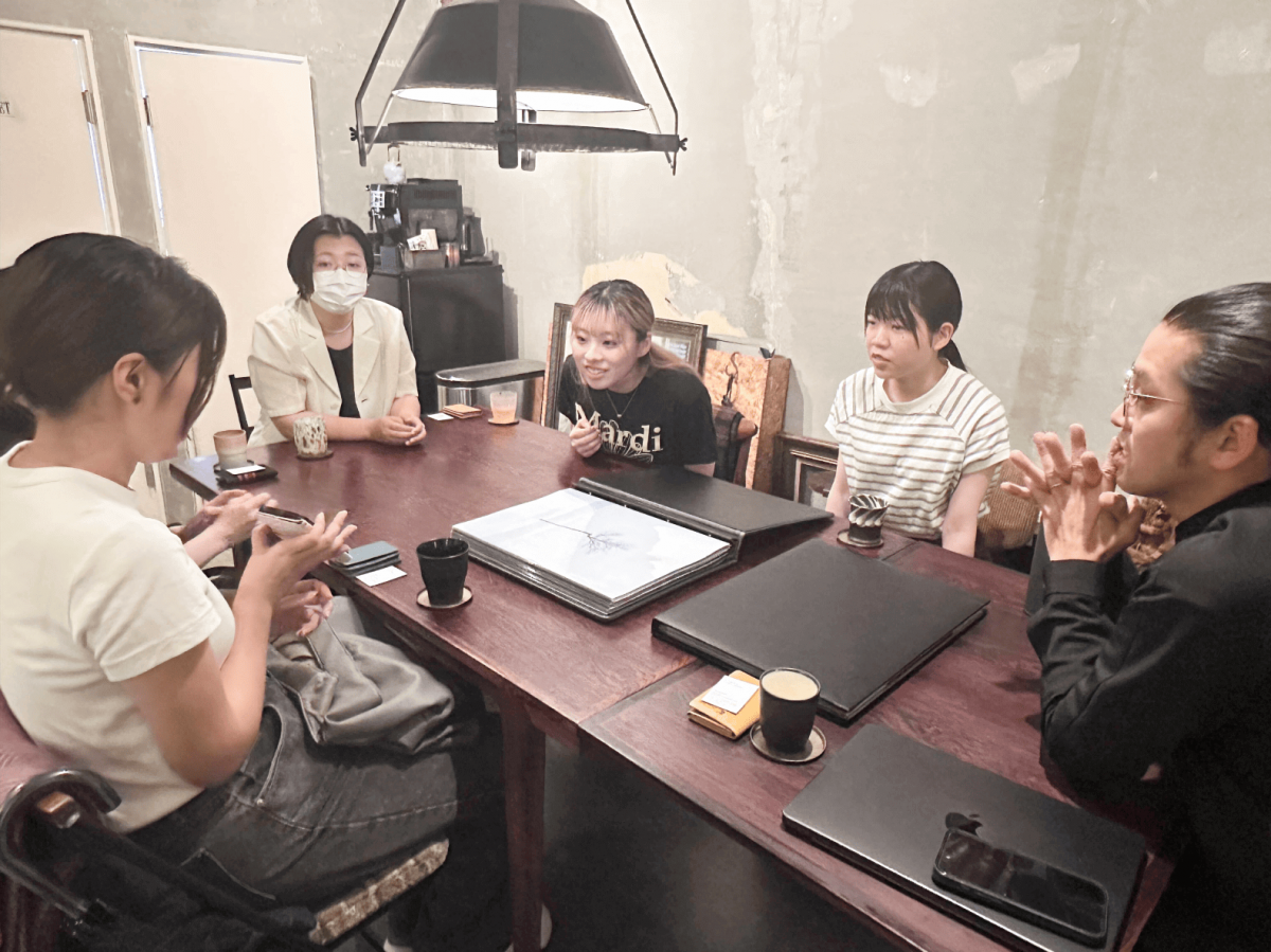 テーブルを囲んで談笑する男女の写真