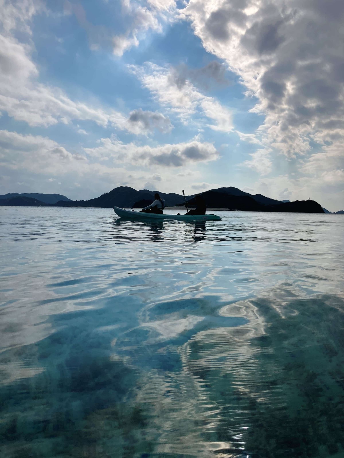 青空がリフレクションする海に、シーカヤックが浮かんでいる
