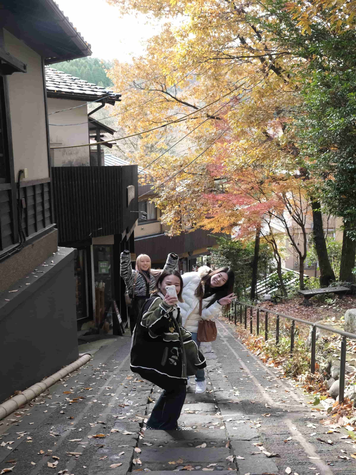 紅葉を背景に写真を撮る牧山さん、那木さん、福永さん