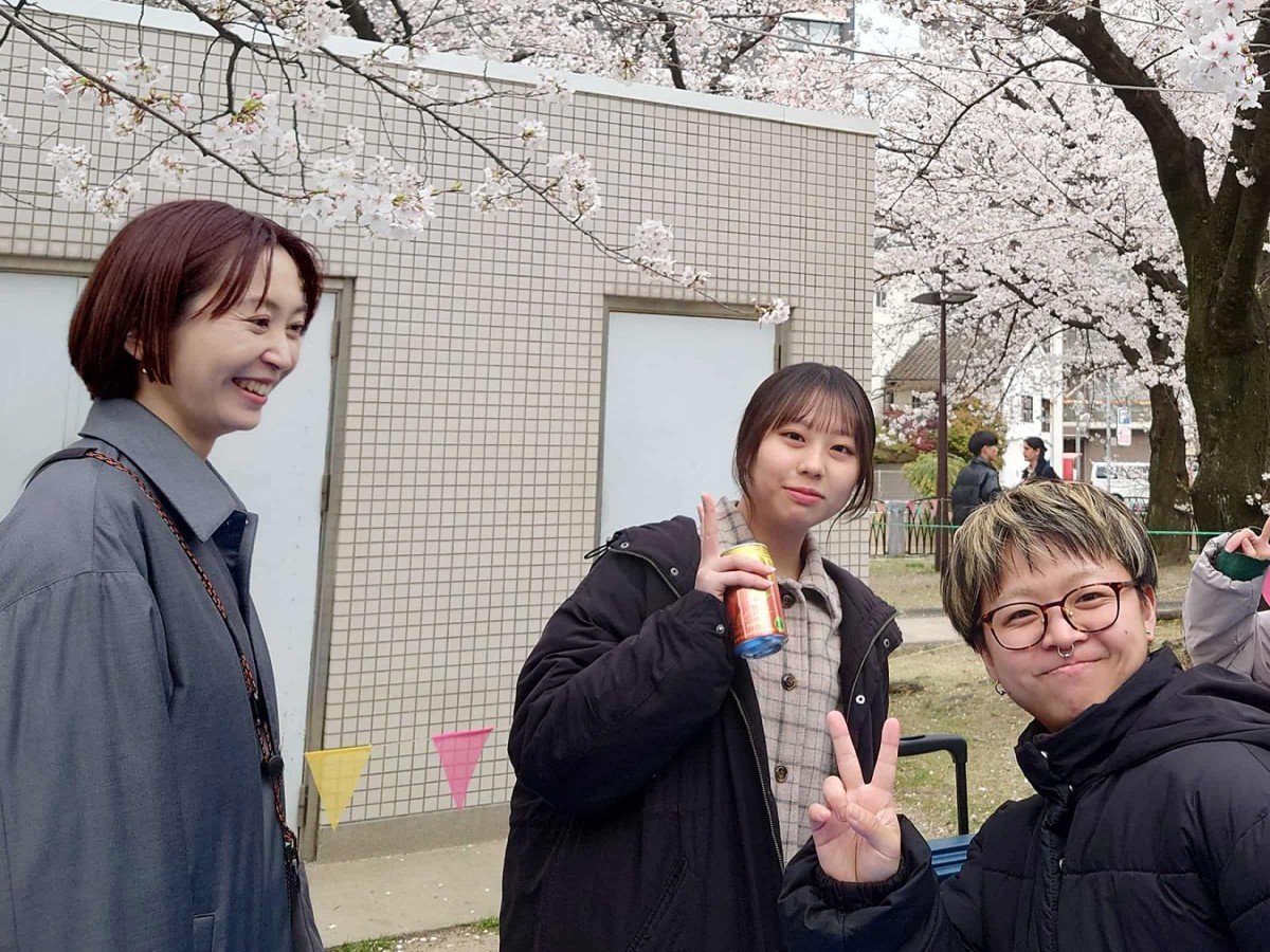 お花見の画像。桜をバックに立つ（左から）岡田さん、諸富さん、木暮さん