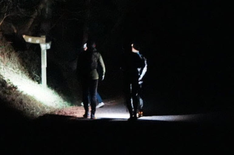 真夜中の山中を走る男性2人