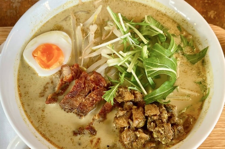 スパイスカレーをベースにしたエスニックラーメン。鶏肉、ゆで卵、もやし、水菜がトッピングされている。