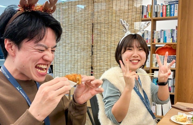 東京オフィスでの忘年会の一場面の写真。トナカイのカチューシャを付けた2人のメンバーがチキンを食べたり、ピースサインをしている。
