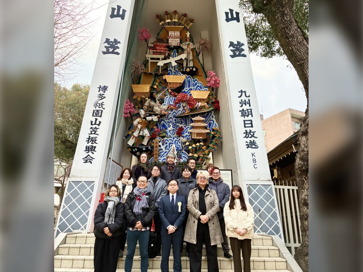 初詣の様子。櫛田神社の飾り山笠の前で、社長をはじめとした社員が並んで立っている。