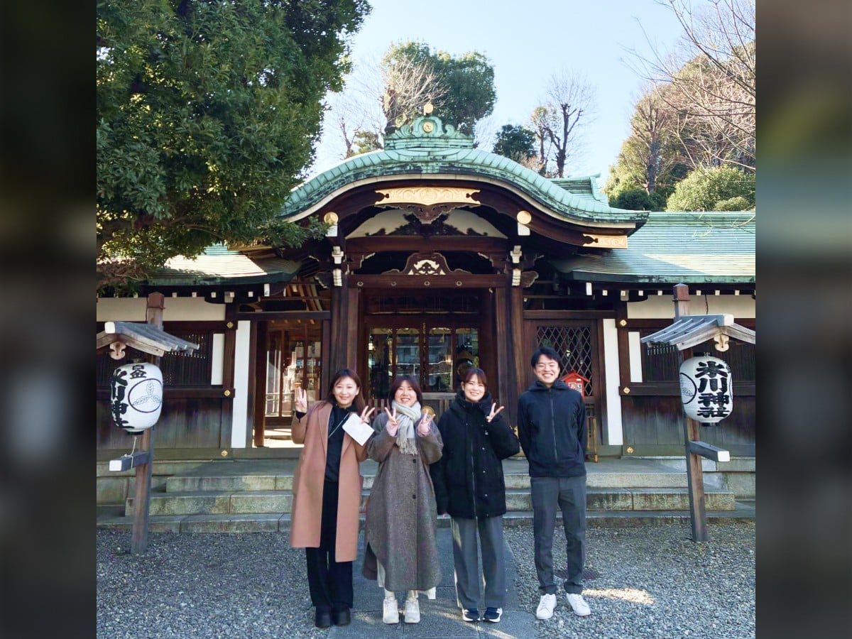 東京オフィスの初詣の様子。お社の前で、社員がピースサインをしたりしながら並んで立っている。