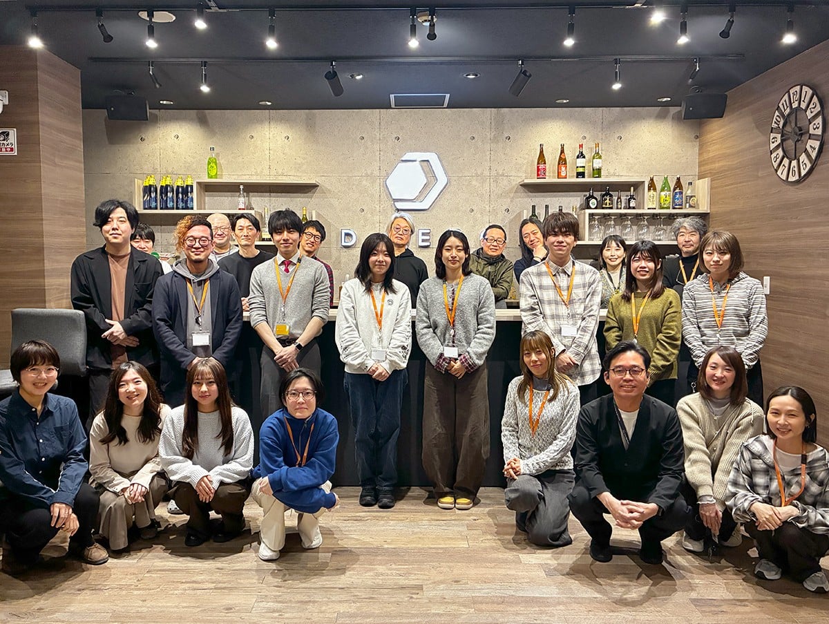 入社式に参加メンバーで写真撮影。中央に新入社員の二人が並んでおり、周りを社員が囲んでいる。