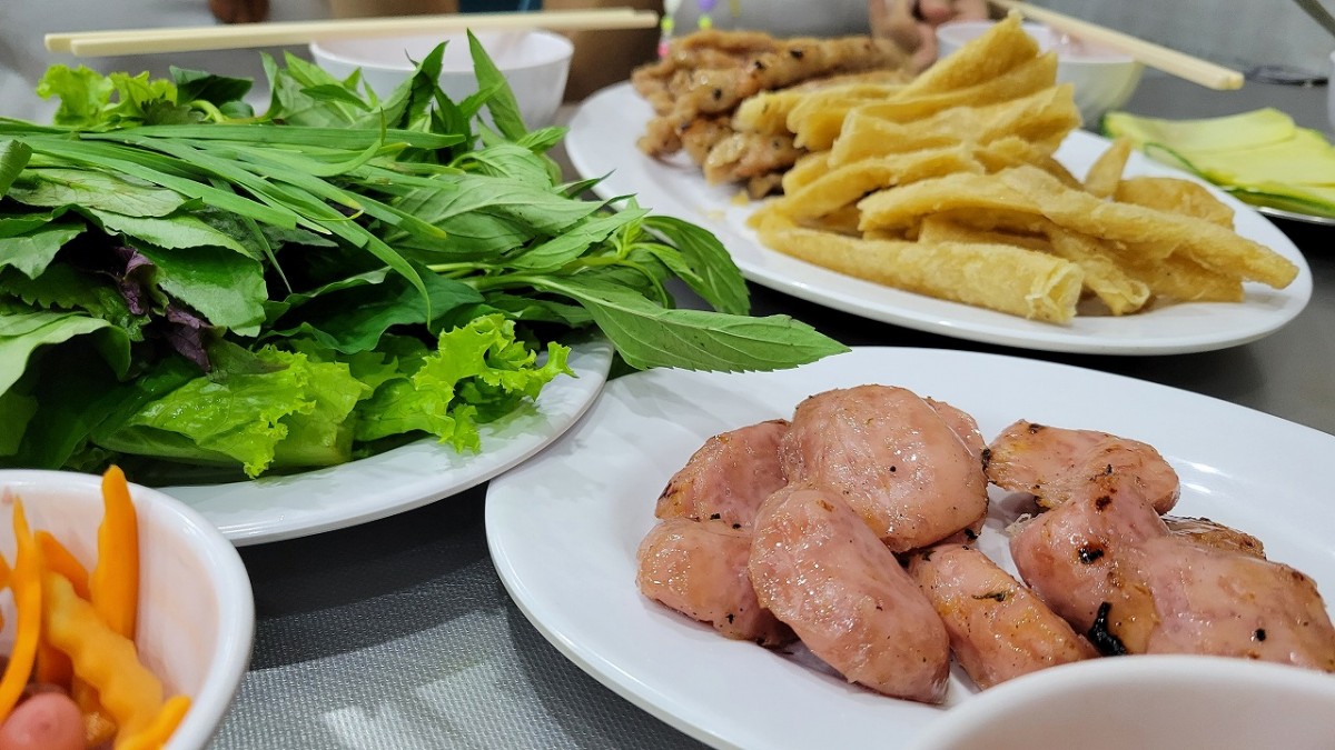 包んで食べる料理。葉っぱやソーセージなどがある写真