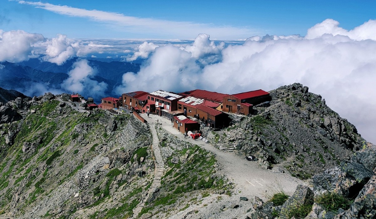 槍ヶ岳山荘を山の上から撮った写真。雲が近く、晴れている様子